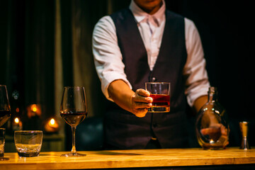 hand holding ice whisky glass, clinking glasses	