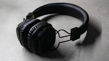 Black headphones on a grey background with light on the side