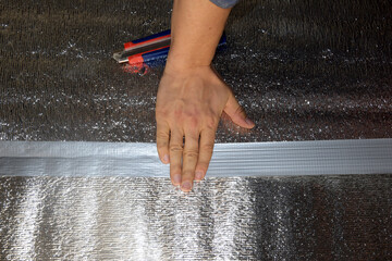A man hides a foil isol with reinforced tape. Male hand holds reinforced tape. Repair in the...