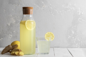 Decanter with ginger water and lemon on white table. Glass of ginger water and decanter.