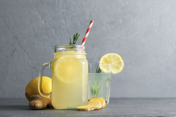 Jar with ginger water and lemon on concrete surface.