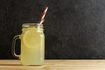 Jar with ginger water and lemon on wooden table with copy space.