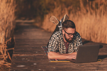 Male blogger writing a blog post while relaxing in nature