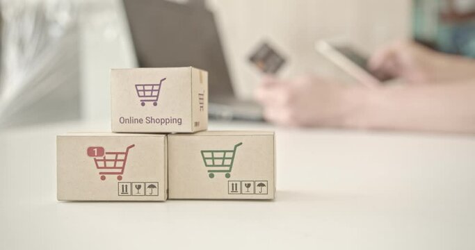 Online shopping / ecommerce and delivery service concept : Paper cartons with a shopping cart or trolley logo, user / customer uses smartphone order things from retailer sites and pay by credit card