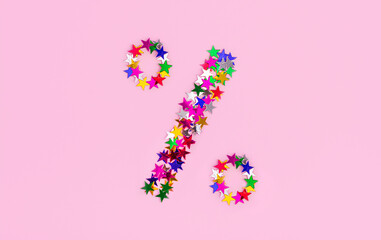 Discount symbol from multi color stars on a pink background. A Percentage Sign, christmas sales