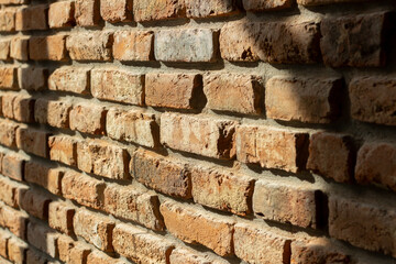 Closeup of old grunge brick wall in natural light. Rough surface, loft style, orange colour. Side view, shallow depth of field, texture or background.