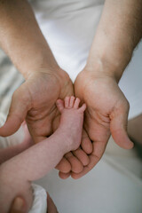 Male hand holding newborn baby's feet. Father with his baby. Family, birth concept. Health, care, love, relationship concept. Close up (Soft focus and blurry)