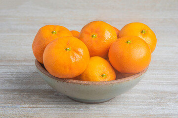Fresh Oranges In A Ceramic Bowl Set On Wood Panel