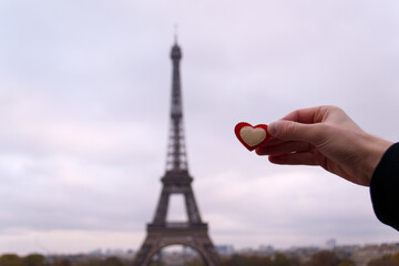 heart in a man's hand against the background of the Eiffel tower
