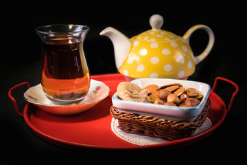 Various dried nuts and tea service. Eating and drinking concept. On black background