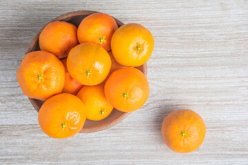 Fresh Oranges In A Ceramic Bowl Set On Wood Panel