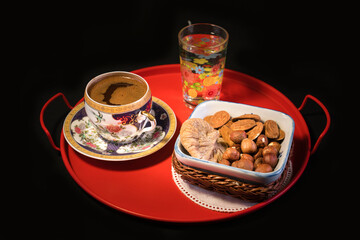 Alongside Turkish coffee presentation, various dried nuts. On black background