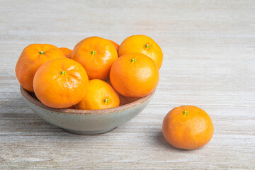 Fresh Oranges In A Ceramic Bowl Set On Wood Panel