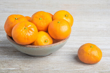 Fresh Oranges In A Ceramic Bowl Set On Wood Panel