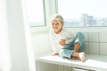 Little cute girl in a bright room, a minimum of objects in the room, the child rejoices, sitting by...