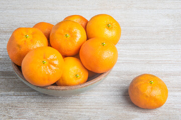 Fresh Oranges In A Ceramic Bowl Set On Wood Panel