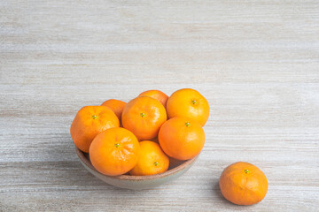 Fresh Oranges In A Ceramic Bowl Set On Wood Panel