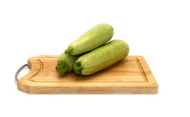 Three zucchini on a cutting board on a light background. Natural product. Natural color. Close-up.