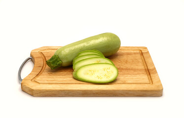 Whole and cut zucchini on a cutting board on a light background. Natural product. Natural color. Close-up.