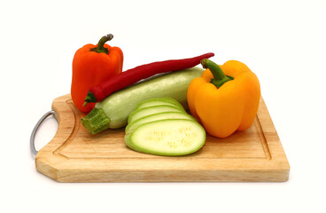Zucchini and ripe sweet pepper of different colors on a cutting board on a light background. Natural product. Natural color. Close-up.
