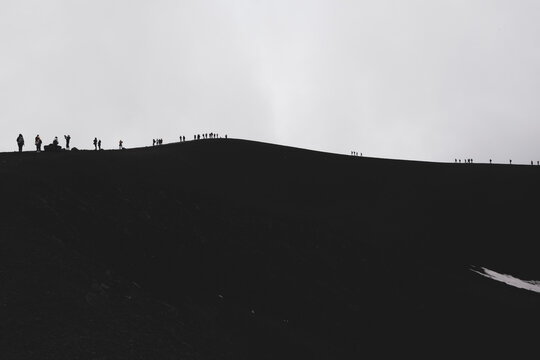 
ETNA NATIONAL PARK, SICILY, ITALY row of tourists walking on the edge of a crater an altitude of 2900 m., at the border with the area of high criticality of the volcano.