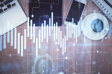 Double exposure of financial graph hologram over desktop with phone. Top view. Mobile trade platform concept.