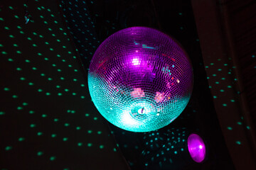 Close up of a glitzy disco ball reflection light onto a black ceiling on a dance floor