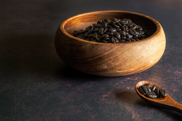 Fototapeta na wymiar Dark Roast Coffee Beans in a Wooden Bowl with Wooden Spoon