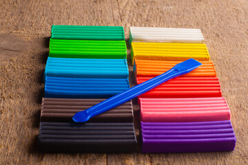 Fototapeta premium many multi-colored plasticine sticks lie on the wooden background.