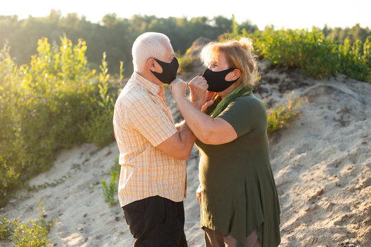 Senior couple in the beach wearing medical mask to protect from coronavirus in summer day, coronavirus quarantine