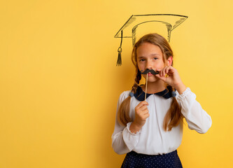 Young student acts like a graduate. Yellow studio background