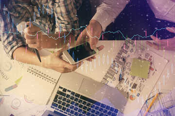 Double exposure of forex graph drawing and man and woman working together holding and using a mobile device. Trade concept.