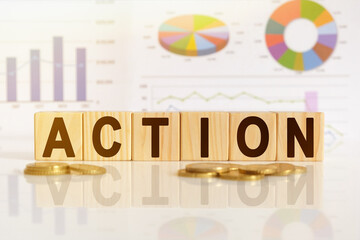 ACTION the word on wooden cubes, cubes stand on a reflective surface, in the background is a business diagram.