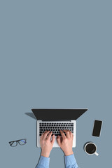 A person uses a laptop on a gray background with a top view and copy space. Vertical
