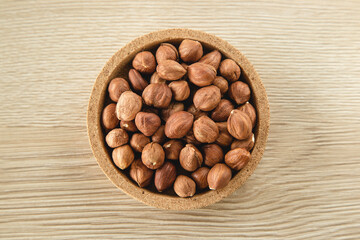 Hazelnuts in the bowl on wooden background, concept of healthy eating vegan food. Top view, selective focus, copy space