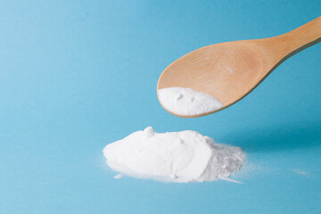 soda is pouring from a wooden spoon, a bunch of soda on a light blue background copy space, eco...