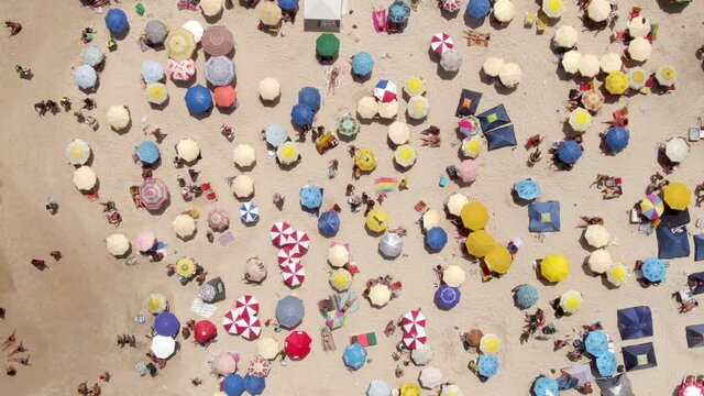 Top down aerial view of colourful sun umbrellas and people relaxing at the beach in Rio de Janeiro, Brazil, fun tropical vacation and summer background. 