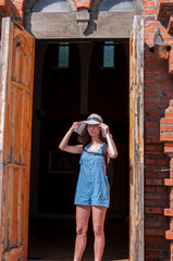 China, Heihe, July 2019: a tourist Girl wearing a hat stands in the doorway of an Orthodox brick Church in a Russian village outside the city of Heihe in the summer
