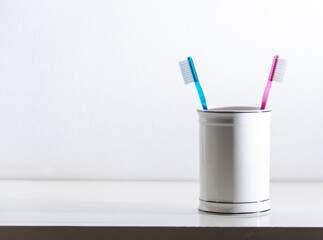 Pair of toothbrushes in a porcelain jar.