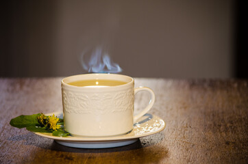 White porcelain cup with dandelion tea on wooden table.