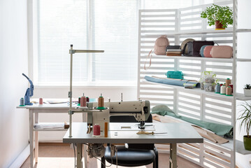 there is sewing equipment in a spacious bright room - obrazy, fototapety, plakaty