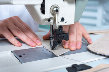 closeup female hands sew a stitch on a sewing machine