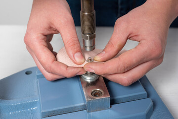 the hands of the master make holes for the buttons on a special installation press