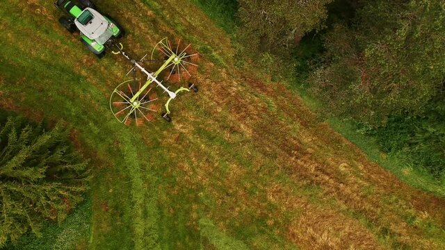 Twin rotor rake mounted on tractor raking grass