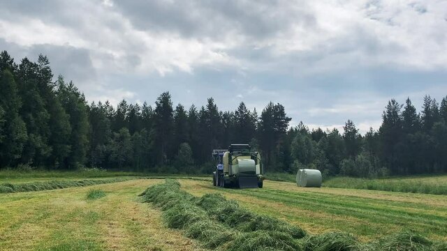 Krone Comprima baler wrapping grass roundbales in plastic