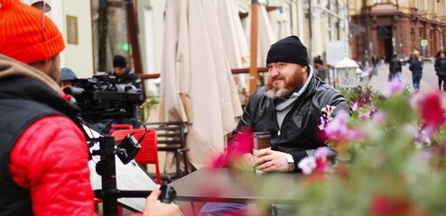 Fototapeta na wymiar Smiling Man With Coffee Sitting At Sidewalk