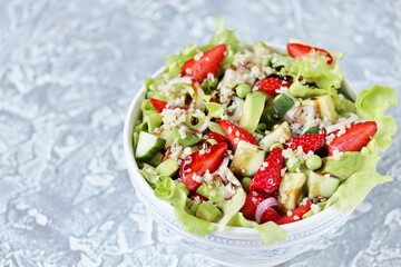 Salad with strawberries, quinoa, avocado, cucumber, lettuce, onions and green peas. vegetarian food.copy space