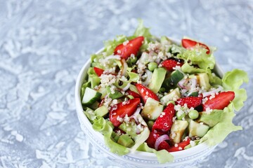Salad with strawberries, quinoa, avocado, cucumber, lettuce, onions and green peas. vegetarian food.copy space