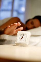 Woman yawning while turning off the ringing alarm clock