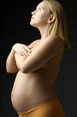 Topless pregnant woman covering her breasts